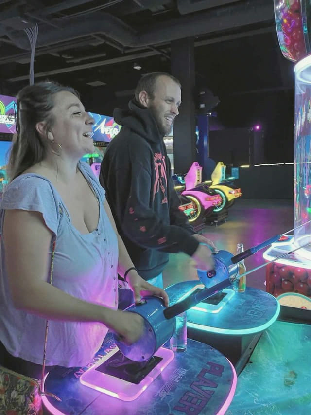 A couple laughing together over an arcade game on a date night