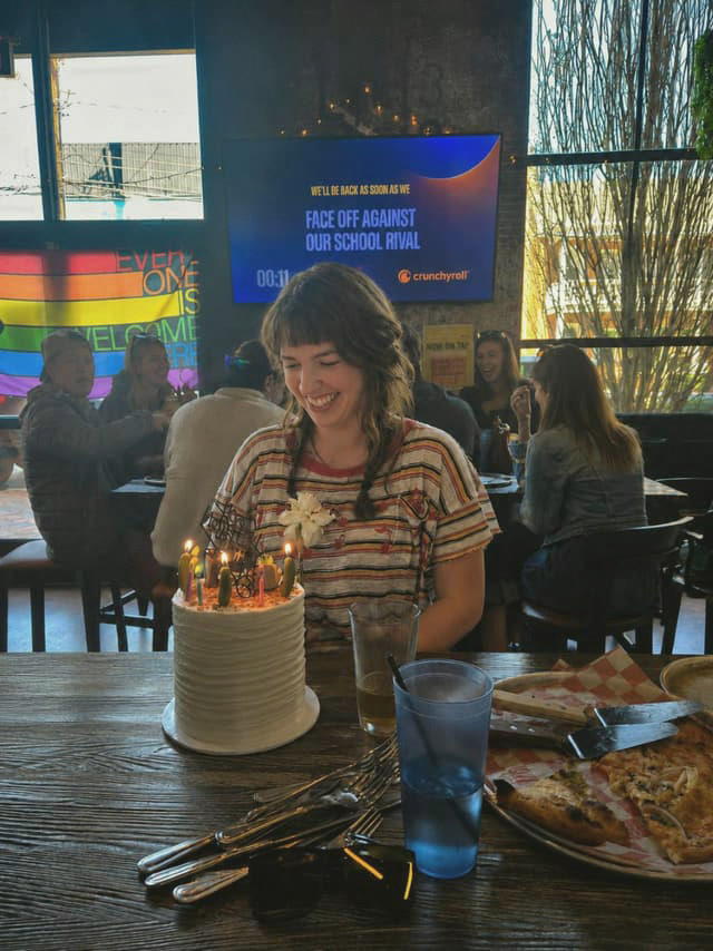 A woman smiling at her birthday cake with lit candles